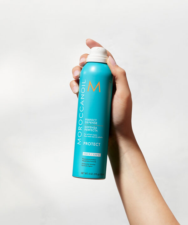 Mano sosteniendo el spray protector térmico Moroccanoil Perfect Defense