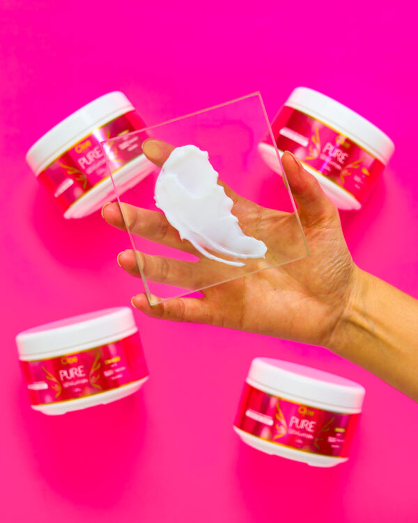 Mano sosteniendo una muestra de la mascarilla Cloe Pure Sensation Color sobre fondo rosa.