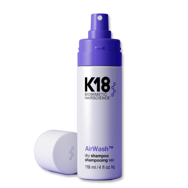 Botella de shampoo en seco K18 AirWash de 118 ml con tapa blanca colocada al lado. La botella es blanca con detalles morados y letras negras, mostrada sobre fondo blanco.