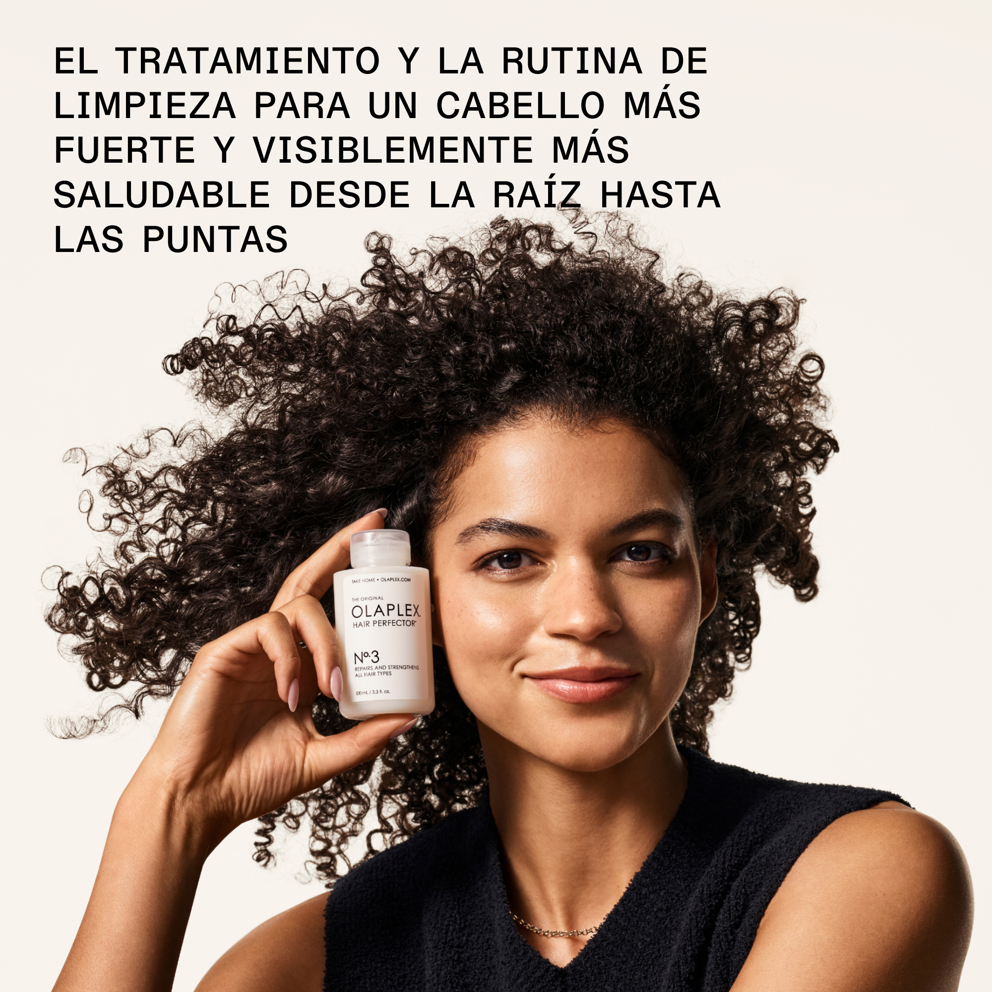 Modelo con cabello rizado y saludable sosteniendo el tratamiento Olaplex Nº.3 Hair Perfector, parte del kit The Greatest Strength.