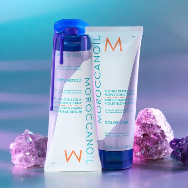 Acondicionador Moroccanoil Blonde Perfecting con tapa abierta y gotas violetas