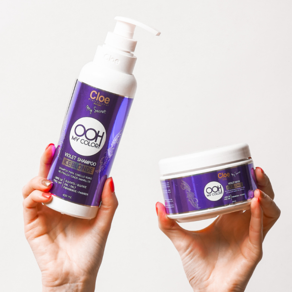 Manos sosteniendo botella de shampoo y envase de mascarilla Cloe OOH My Color Violet Ice Blonde sobre fondo blanco, ambos con etiquetas moradas.