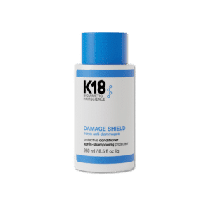 Una botella del K18 Damage Shield Acondicionador de 250 ml. El envase es blanco con una franja azul en la parte superior y un tapón azul brillante. La etiqueta muestra el nombre del producto en negro y azul con el logo K18 Biomimetic Hairscience. Este acondicionador protector está diseñado para fortalecer y suavizar el cabello.