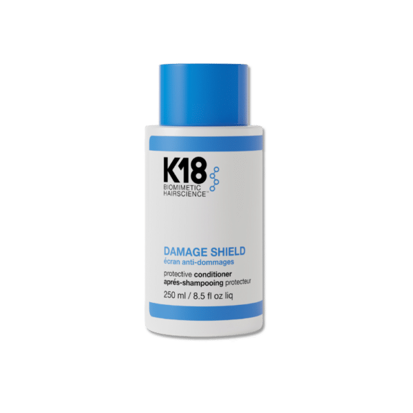 Una botella del K18 Damage Shield Acondicionador de 250 ml. El envase es blanco con una franja azul en la parte superior y un tapón azul brillante. La etiqueta muestra el nombre del producto en negro y azul con el logo K18 Biomimetic Hairscience. Este acondicionador protector está diseñado para fortalecer y suavizar el cabello.