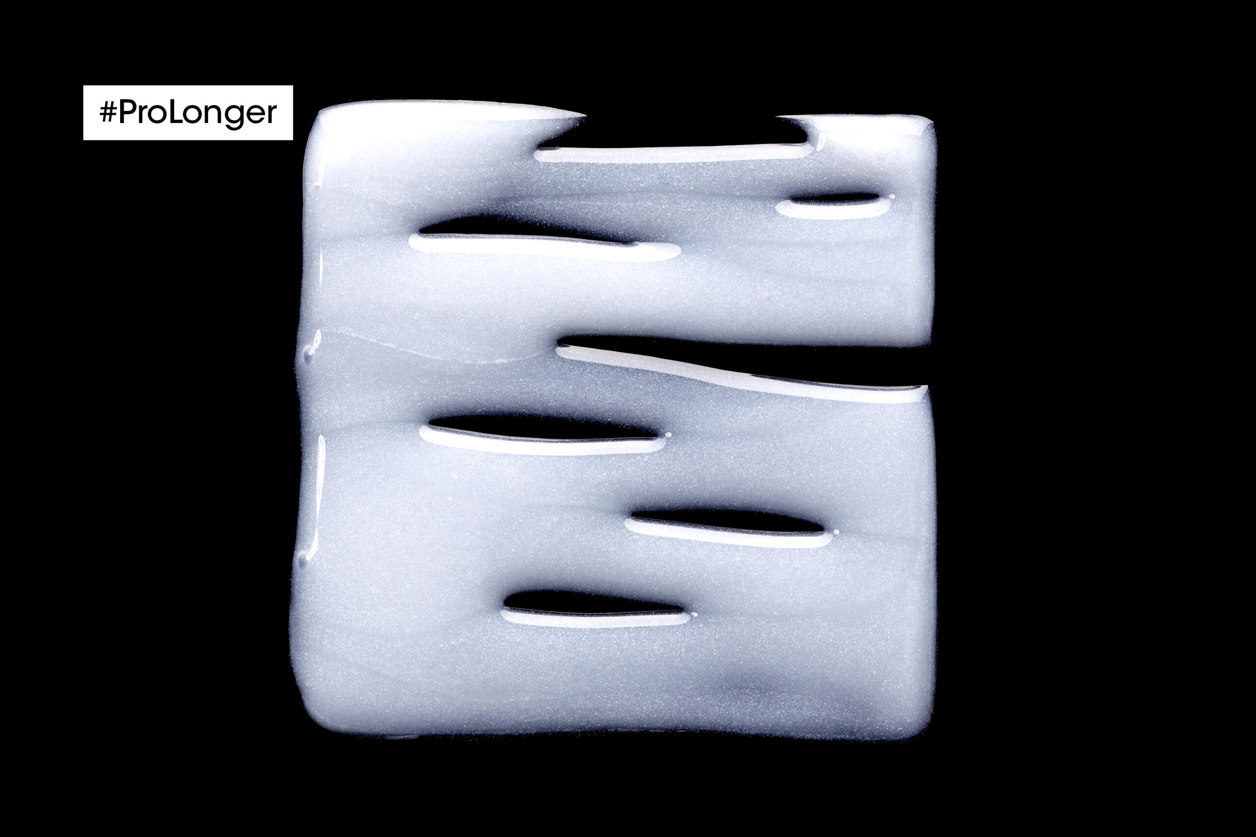 Textura perlada del shampoo Pro Longer de L’Oréal Professionnel sobre fondo negro