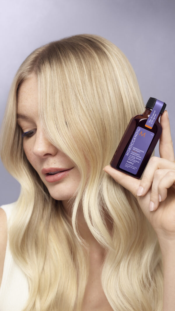 Modelo rubia sosteniendo el Tratamiento Moroccanoil Purple